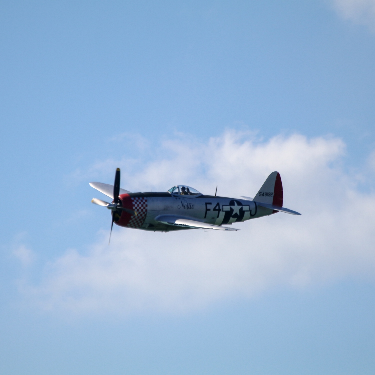 Republic P-47 Thunderbolt flying left against cloudy blue sky