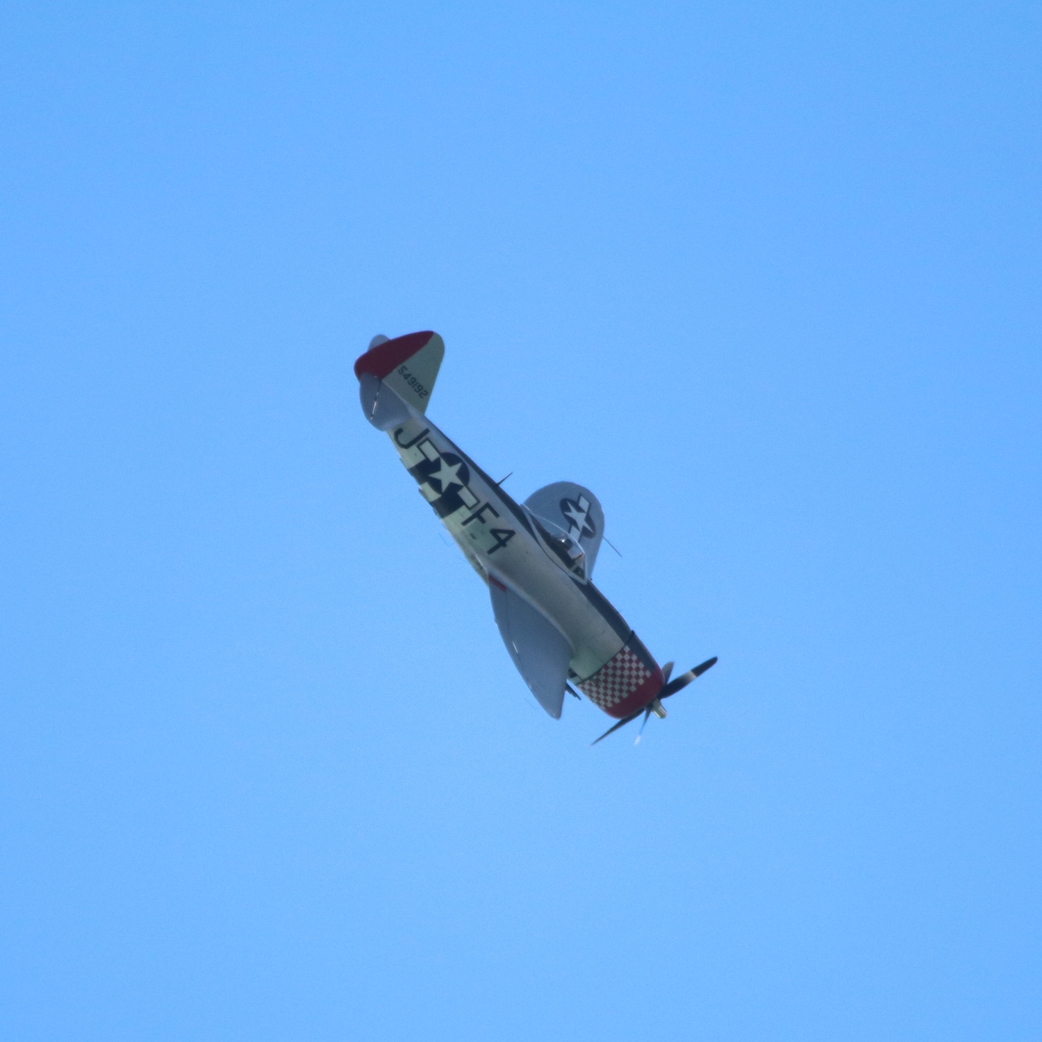 Republic P-47 Thunderbolt flying down and right against clear blue sky