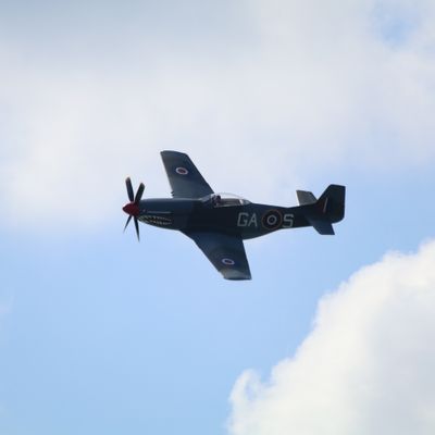 North American P-51 Mustang flying left with top side visible against cloudy sky
