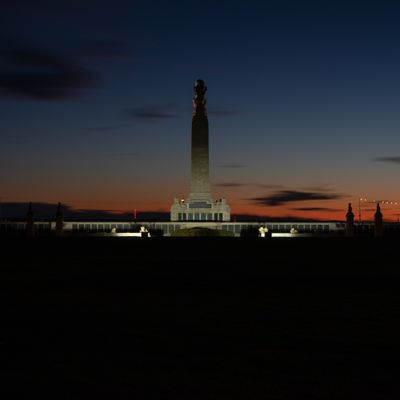 Portsmouth Cenotaph sillouetted against the orange and blue sky of sunset. Partially lit by floodlights.