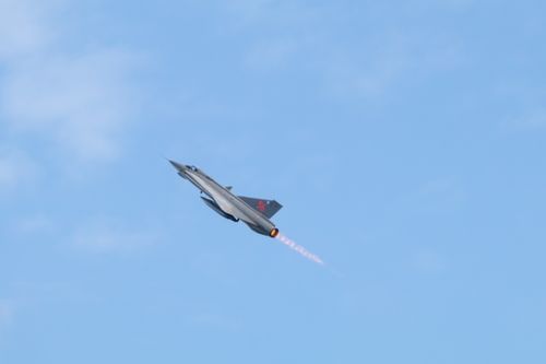 Saab Draken flying up and left with afterburners on in long trail against blue sky