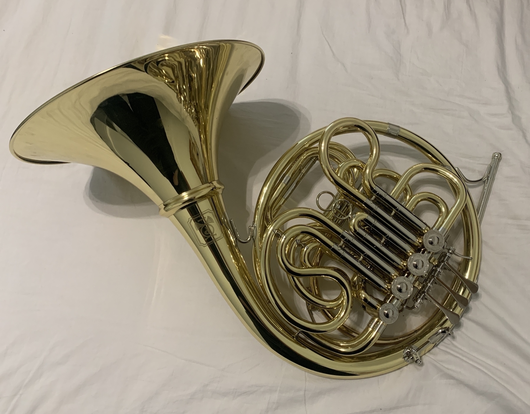 My new French horn sat on a white bed sheet