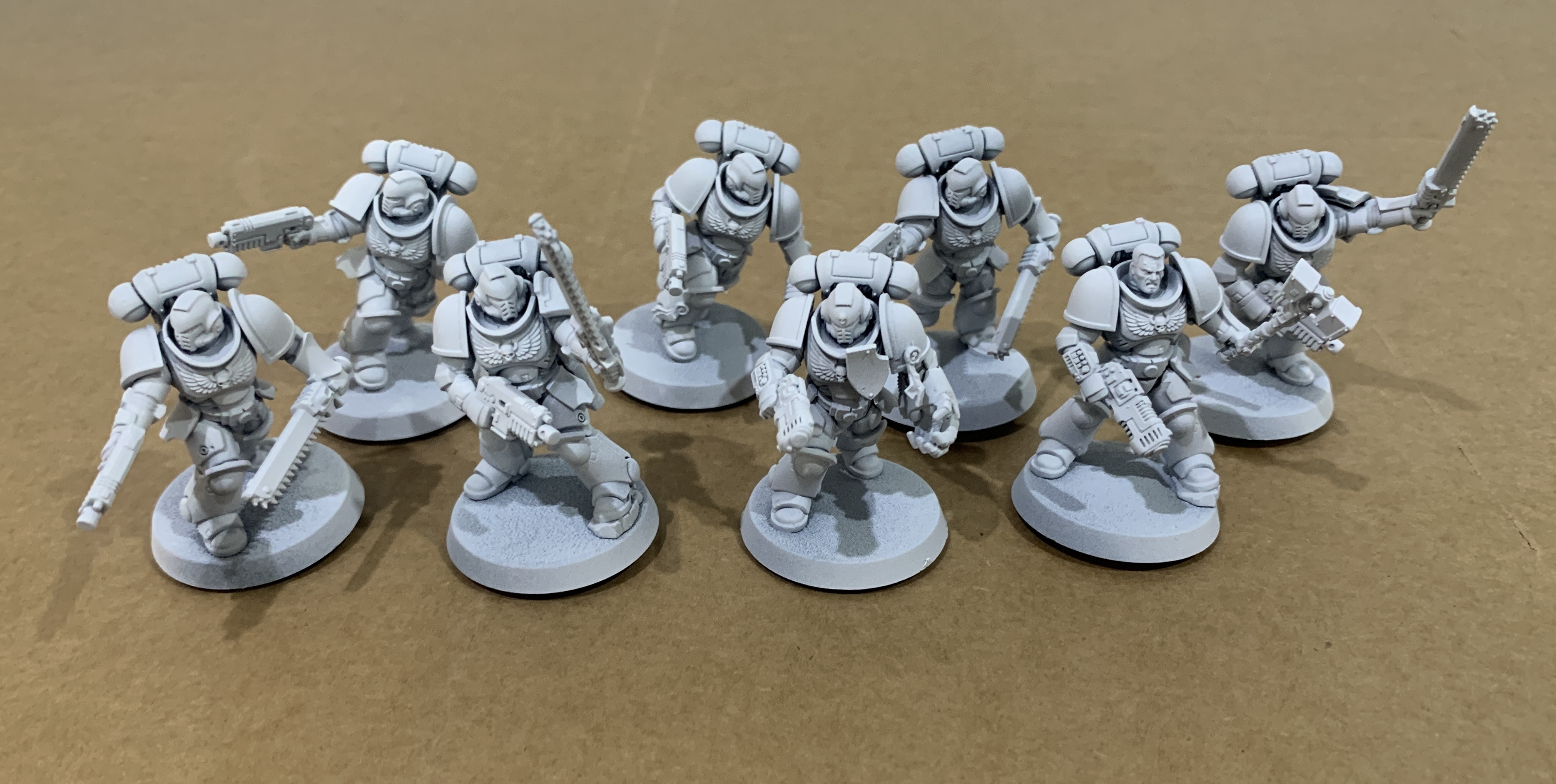 8 space marine assault intercessors primed white on a brown cardboard background