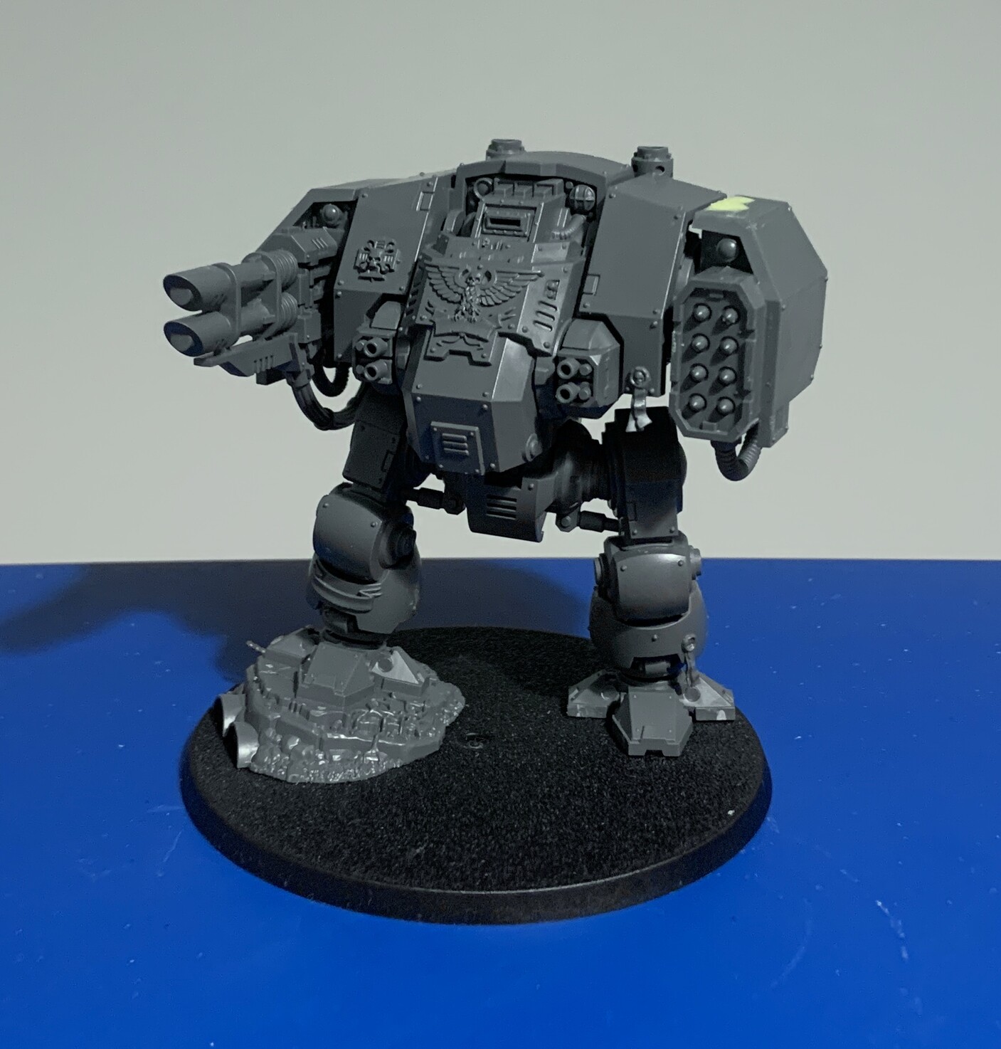 Ballistus dreadnought. The dreadnought is stood on its two legs with one foot on a raised rocky outcrop. The left hand weapon is a pair of long barrelled laser weapons and the right hand weapon is 8 missiles in a grid in a housing.