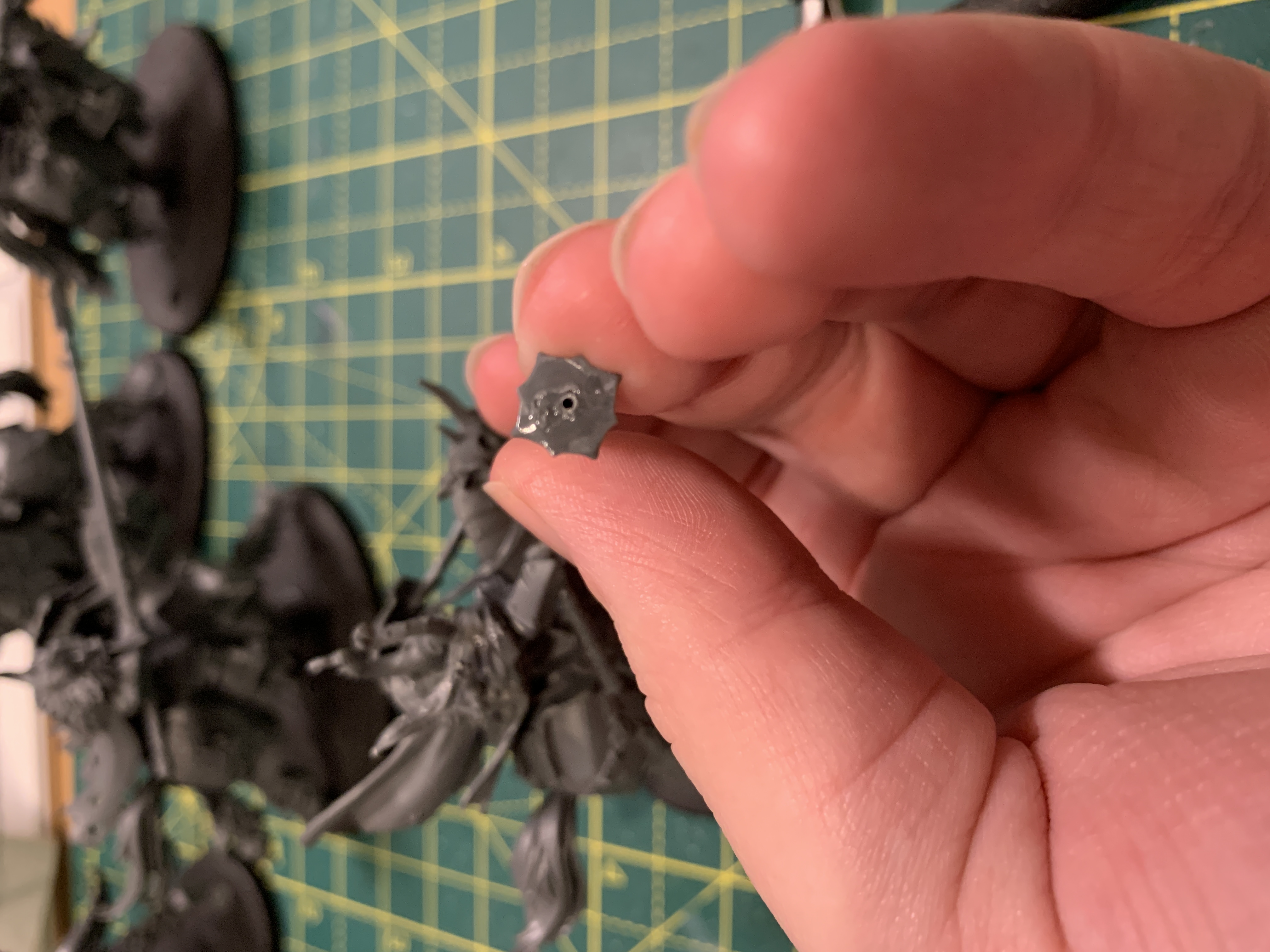 Me holding a Slaves to Darkness Chaos Knight lance with the tip facing away from the camera showing the 0.7mm hole I've just drilled to pin it to the model. In the background is a green and yellow cutting mat and several other models
