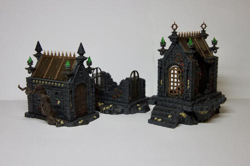 Three dark grey stone mausoleums models in various states of decay. The leftmost is mostly intact and has a tree beside it, it has a wooden roof and braziers around its roof with green smoke. The middle is much shorter and has been reduced to almost rubble, it has a pair of dark iron gates. The rightmost has been split in two and you can see straight through it. It also has braziers around its roof with green smoke coming out of them. They are all on dirt mounds of various heights with skulls and other skeleton parts littered around 