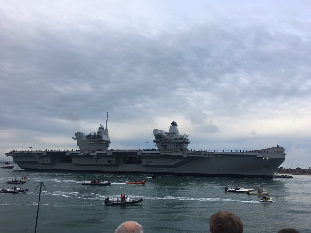 Photo of the HMS Queen Elizabeth aircraft carrier with a number of small boats in escord