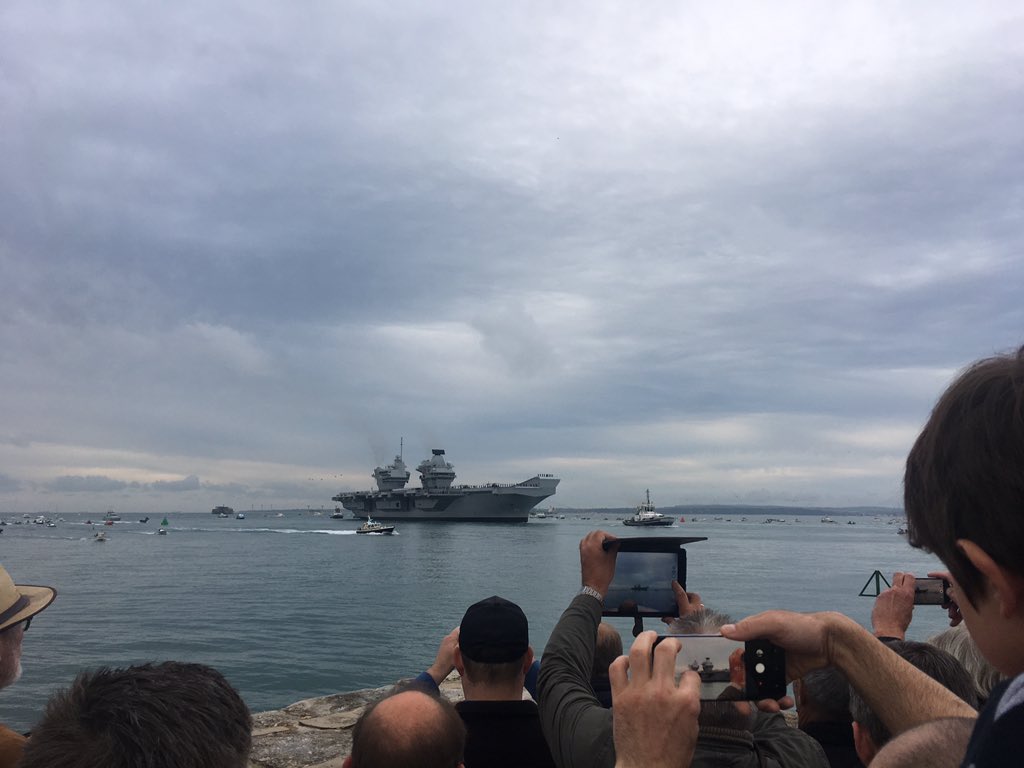 Photo of the HMS Queen Elizabeth aircraft carrier with a number of small boats in escord