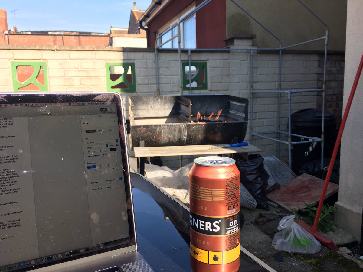 Photo of bbq in background in a garden with white painted walls. In for foreground is my laptop and a can of Mangers cider